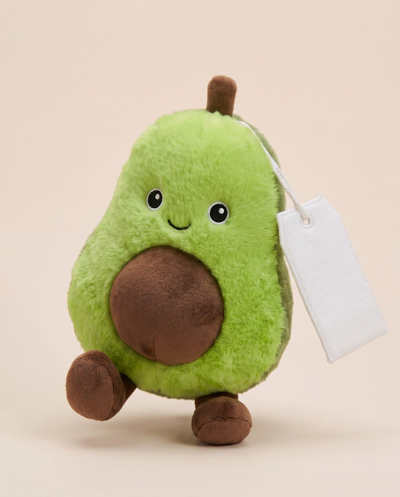 Arlo the Avocado TagTales plush standing on a cream background, with the blank white fleece personalisation tag hanging from a cord