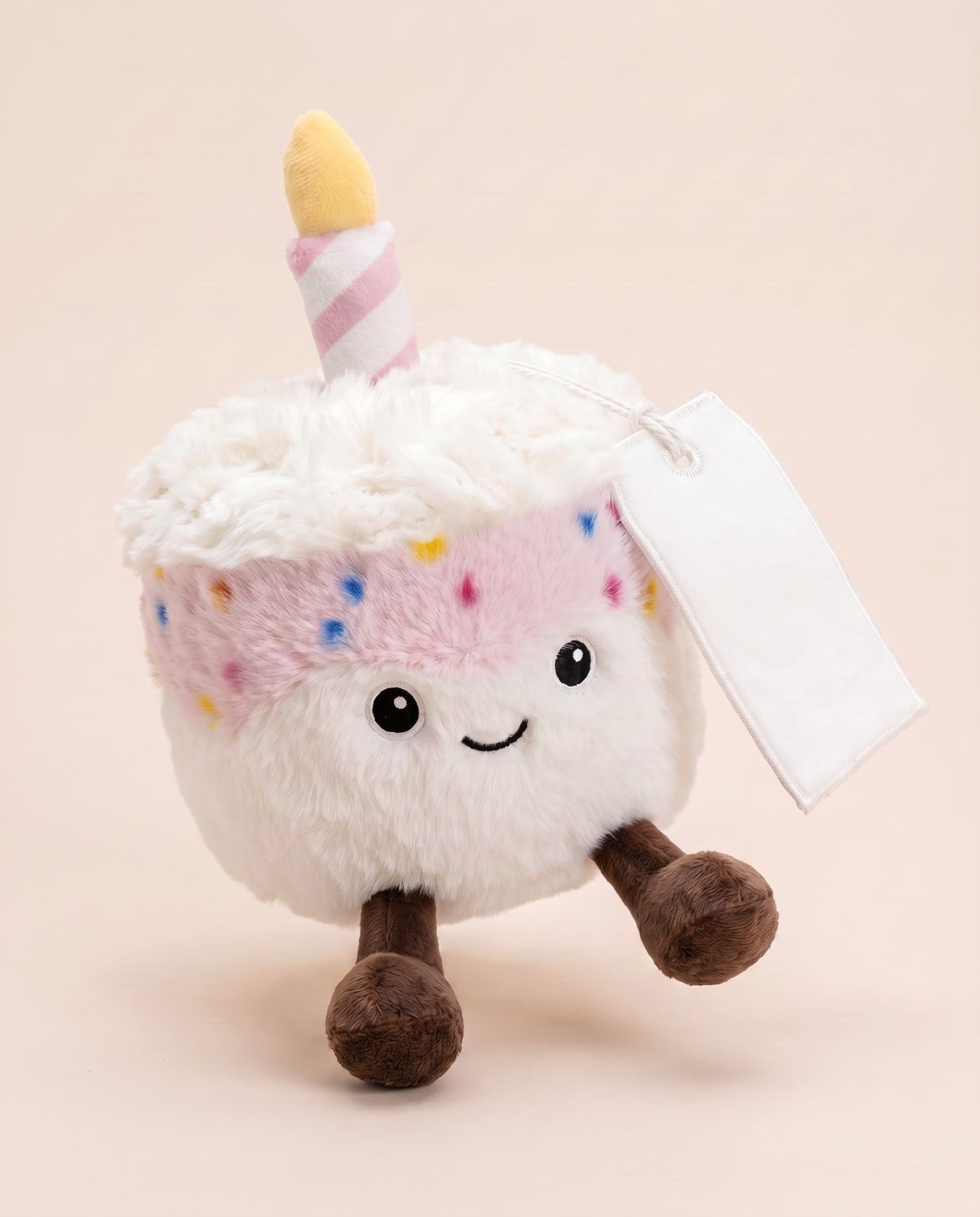 Betty the Birthday Cake (Pink) TagTales plush standing on a cream background, with the blank white fleece personalisation tag hanging from a cord