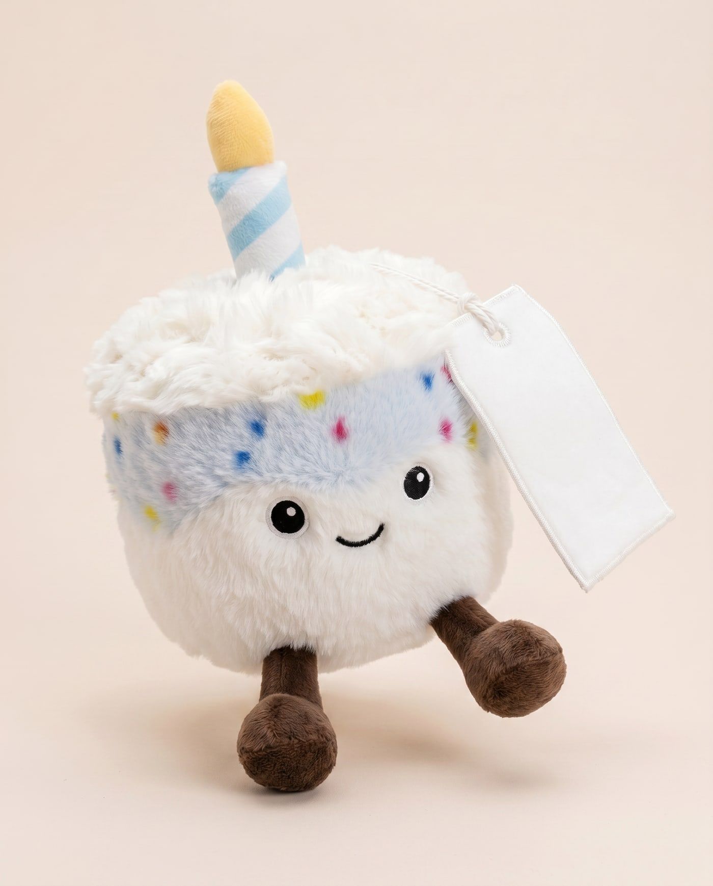 Bobby the Birthday Cake (Blue) TagTales plush standing on a cream background, with the blank white fleece personalisation tag hanging from a cord