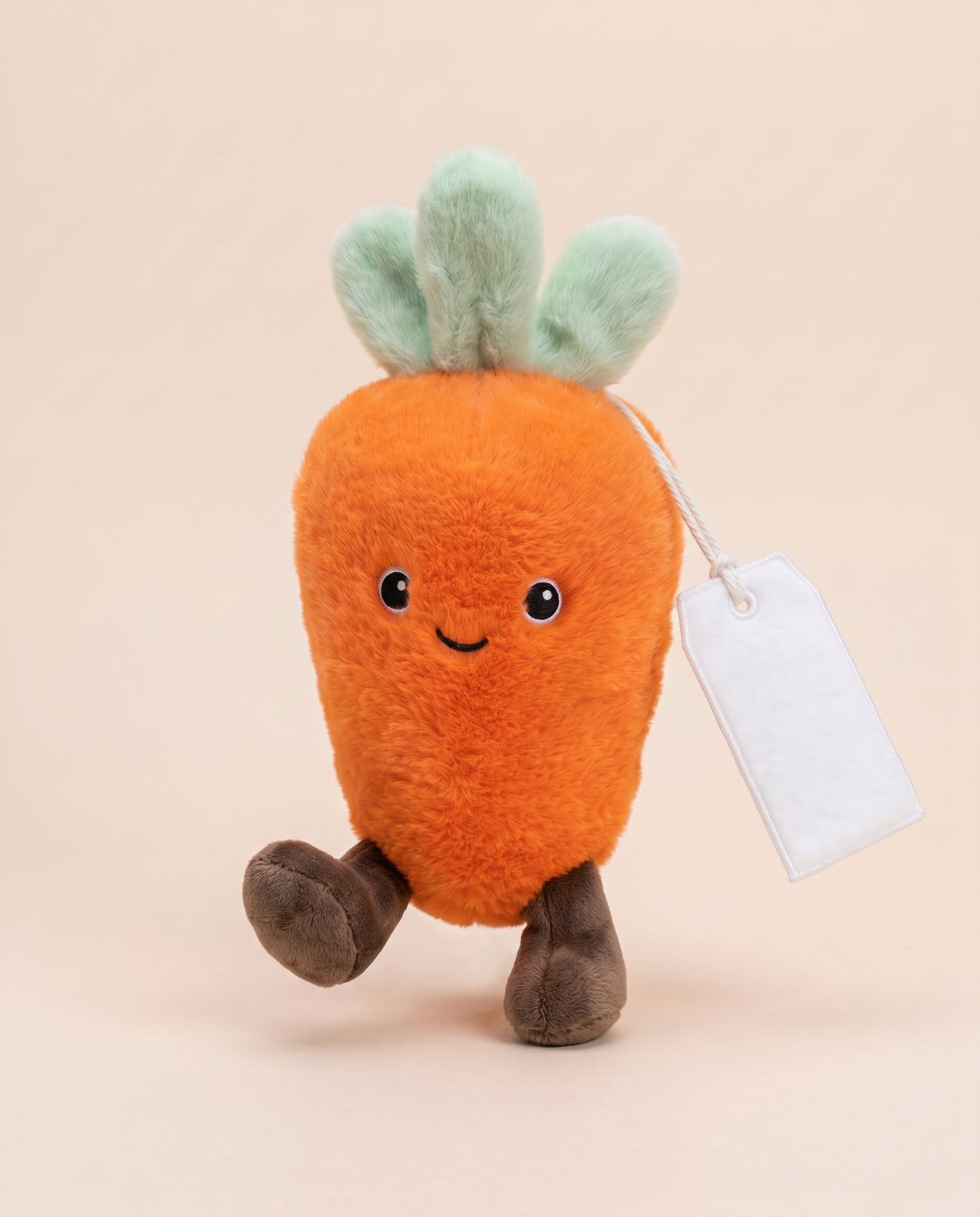Charlie the Carrot TagTales plush standing on a cream background, with the blank white fleece personalisation tag hanging from a cord