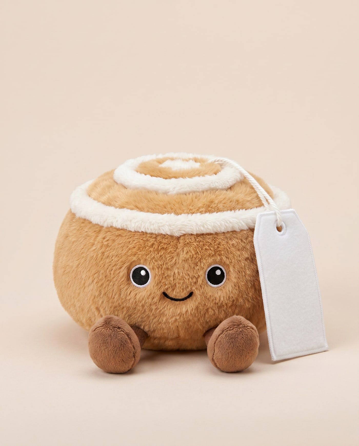 Cindy the Cinnamon Bun TagTales plush sitting down, showing the blank white fleece personalisation tag