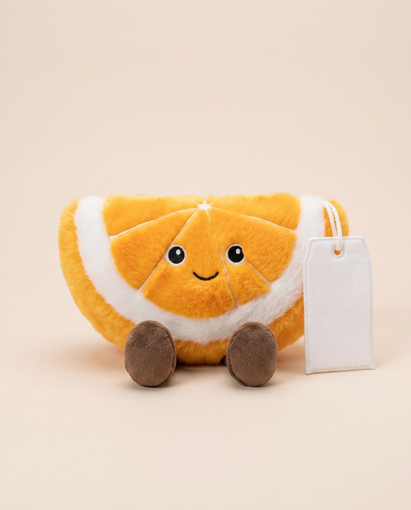 Ollie the Orange Slice TagTales plush sitting down, showing the blank white fleece personalisation tag
