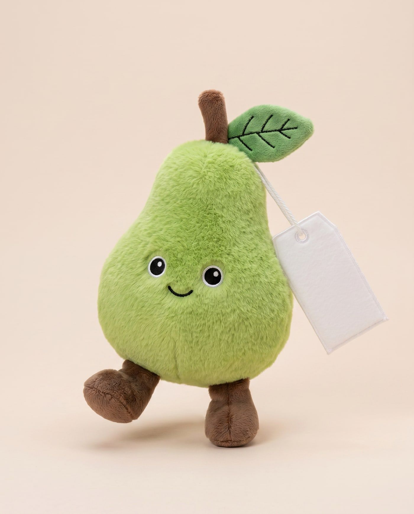 Percy the Pear TagTales plush standing on a cream background, with the blank white fleece personalisation tag hanging from a cord