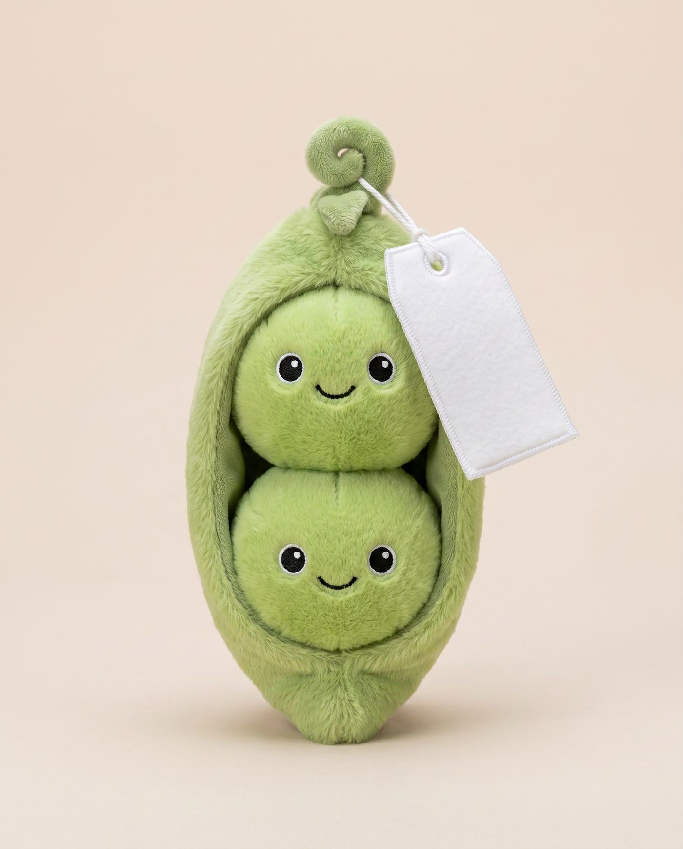 Pip & Polly the Peas TagTales plush lying in their pod on a cream background, with the blank white fleece personalisation tag hanging from a cord