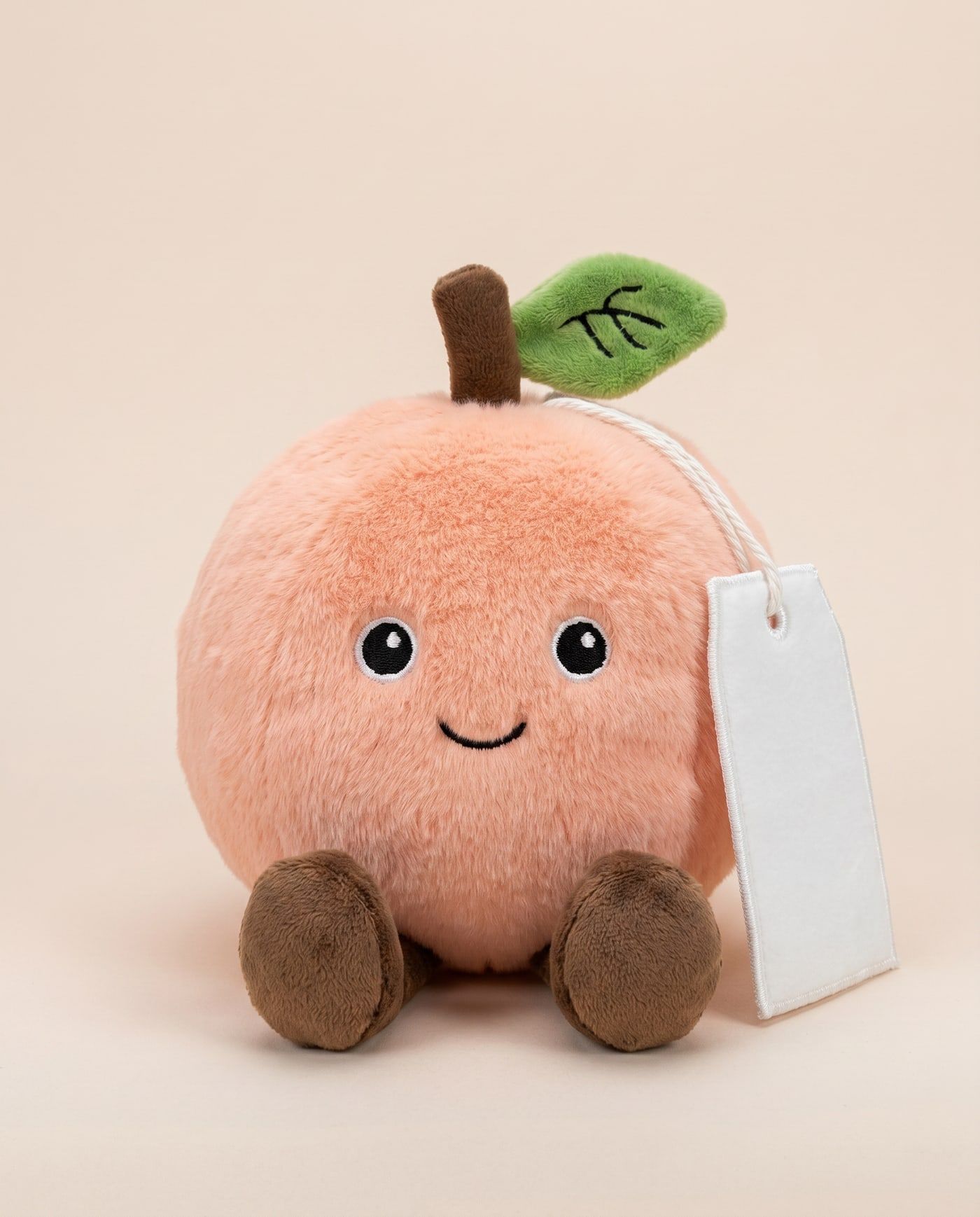 Poppy the Peach TagTales plush sitting down, showing the blank white fleece personalisation tag