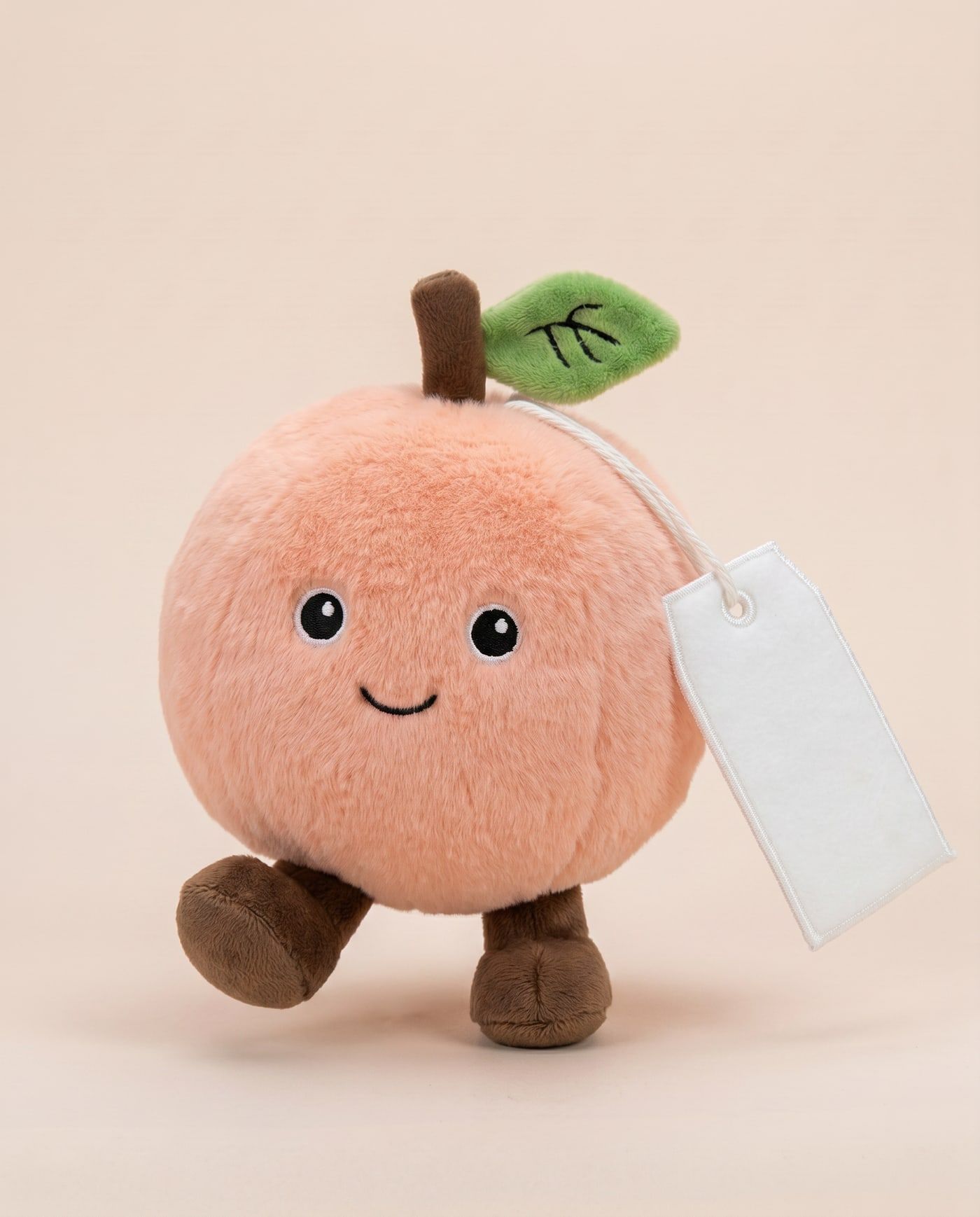 Poppy the Peach TagTales plush standing on a cream background, with the blank white fleece personalisation tag hanging from a cord
