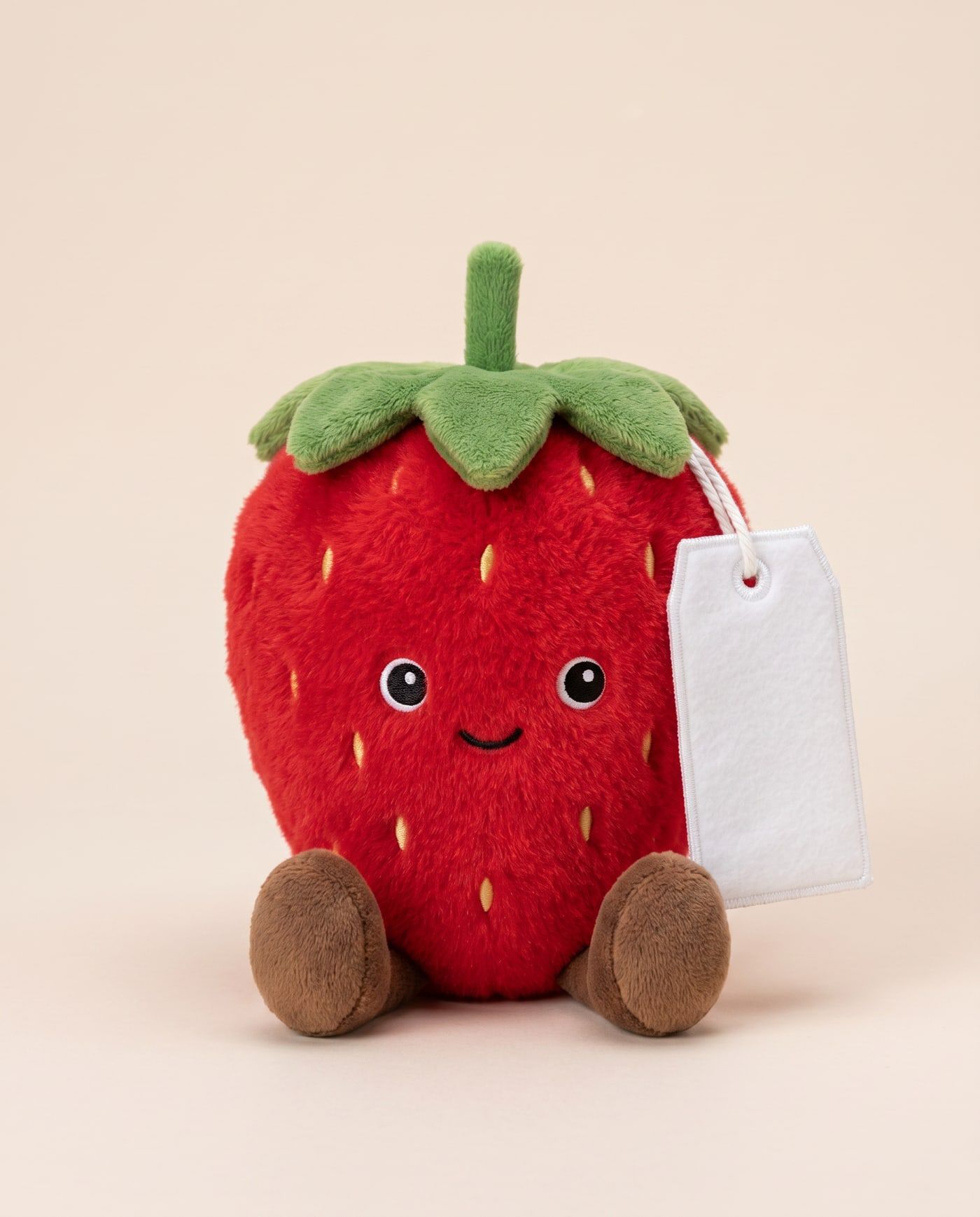 Stevie the Strawberry TagTales plush sitting down, showing the blank white fleece personalisation tag