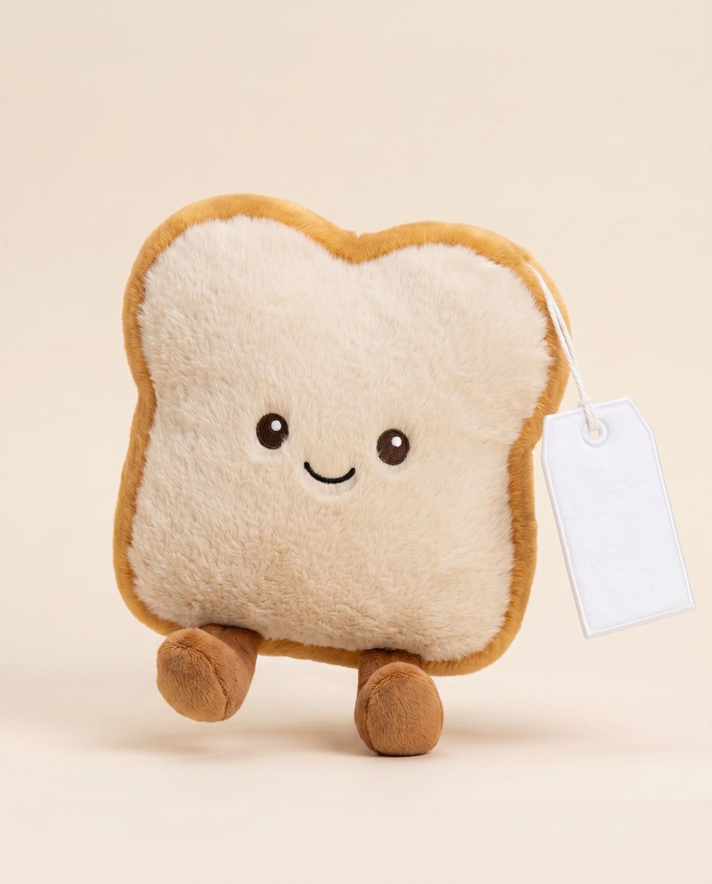 Toby the Toast TagTales plush standing on a cream background, with the blank white fleece personalisation tag hanging from a cord