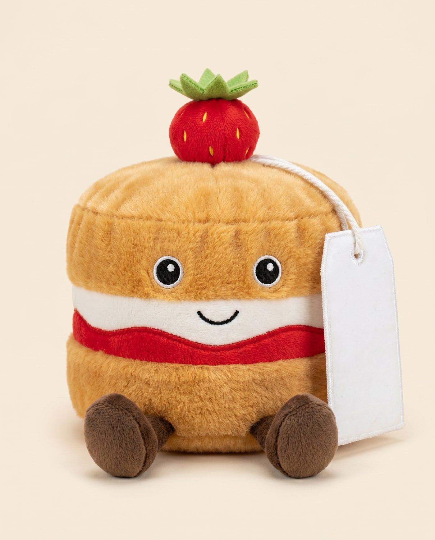 Vicky the Victoria Sponge TagTales plush sitting down, showing the blank white fleece personalisation tag