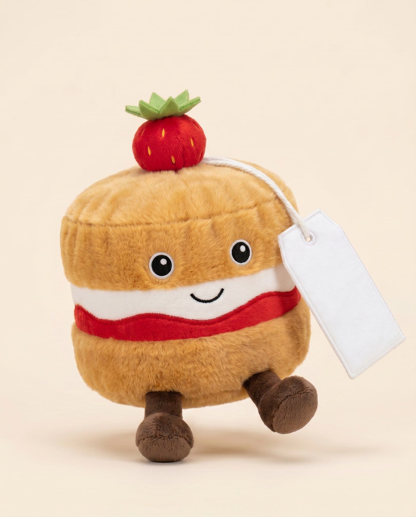 Vicky the Victoria Sponge TagTales plush standing on a cream background, with the blank white fleece personalisation tag hanging from a cord